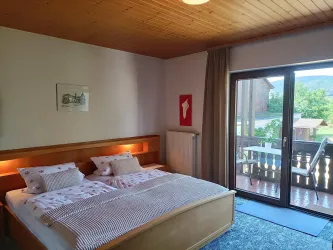 Zimmer 4 ist ein Doppelzimmer im Gästehaus an der Weinstraßenmitte in Neustadt-Diedesfeld – mit Holzmöbeln, beleuchtetem Bettkopfteil und Balkon mit Blick über Garten, Weinberge und Pfälzerwald.