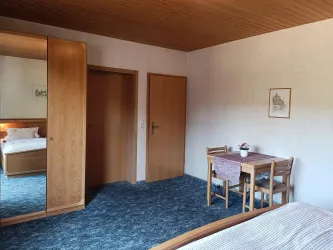 Zimmer 4 bietet einen großen Kleiderschrank mit Spiegel und eine kleine Sitzecke.