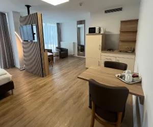 Eine moderne Wohnung mit einem offenen Wohnbereich und einer Küchenzeile. Der Raum ist hell und einladend mit Holzboden und gemütlichen Möbeln.
