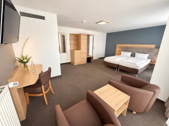 Ein modernes Hotelzimmer mit zwei Betten und einem großen Fenster. Die Einrichtung ist minimalistisch und in sanften Farben gehalten.
