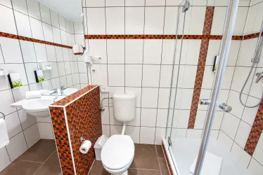 Ein modernes Badezimmer mit hellen Fliesen und bunten Akzenten. Es verfügt über eine Dusche, ein Waschbecken und eine Toilette.