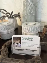 Ein eleganter Tisch mit dekorativen Kerzenhaltern und einer Visitenkarte für eine Ferienwohnung. Die Atmosphäre ist gemütlich und einladend.