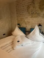 Ein gemütliches Schlafzimmer mit einem großen Bett und dekorativen Kissen. Die Wände sind mit einem rustikalen Material gestaltet.