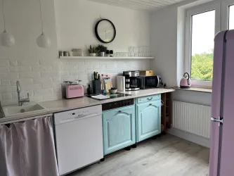 Eine moderne Küche mit hellen Farben und einer eleganten Einrichtung. Die Möbel sind funktional und stilvoll, mit einem wunderschönen Blick nach draußen.