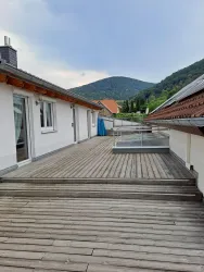 Eine großzügige Dachterrasse mit Holzverkleidung und Blick auf die umliegenden Berge.