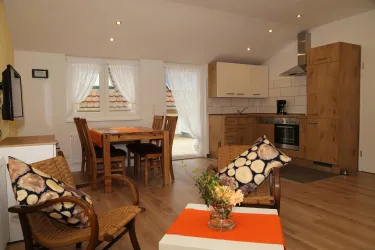 Eine helle Küche mit modernem Design und Holzfarbe. Der Raum ist gemütlich mit einem Essbereich und bequemen Sitzgelegenheiten.