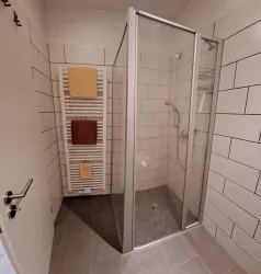 Ein modernes Badezimmer mit einer eleganten Duschkabine. Handtücher hängen an einem Heizkörper in der Nähe der Dusche.