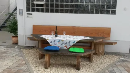 Ein gemütlicher Tisch mit Holzbank und Kissen. Ein schattiges Plätzchen an heißen Sommertagen läd zum Verweilen ein.