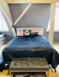 Ein gemütliches Schlafzimmer mit einem großen Bett und einer eleganten Bank. Die Wände sind in einem neutralen Farbton gehalten und die Dekoration ist stilvoll.