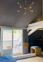 Ein modernes Zimmer mit einem Fenster und einem kleinen Balkon. Es hat eine stilvolle Beleuchtung und Holzdetails.