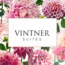 Ein elegantes Logo mit dem Schriftzug "VINTNER SUITES", umgeben von bunten Dahlien und Pflanzen. Die Blumen verleihen dem Design eine frische und ansprechende Atmosphäre.
