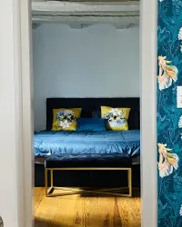 Ein stilvolles Schlafzimmer mit einem doppelten Bett und dekorativen Kissen. Die Wände sind mit einer bunten Tapete verziert und der Boden ist aus Holz.