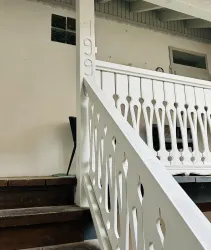 Eine weiße Treppe mit einem dekorativen Geländer. An der Wand ist die Nummer 199 zu sehen.