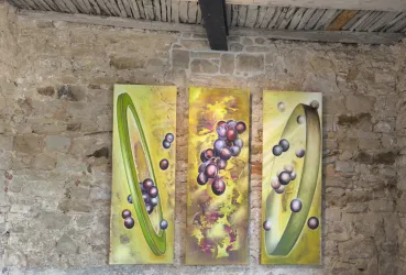 Drei abstrakte Gemälde mit lila und grünen Elementen hängen an einer steinernen Wand. Die Kunstwerke zeigen dynamische Formen und Farben, die an eine moderne Interpretation von Früchten erinnern.