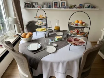 Ein festlich gedeckter Tisch mit mehreren Etagen von Frühstücksaufschnitt, Obst und Brötchen. Eine saftige Auswahl für einen genussvollen Start in den Tag.