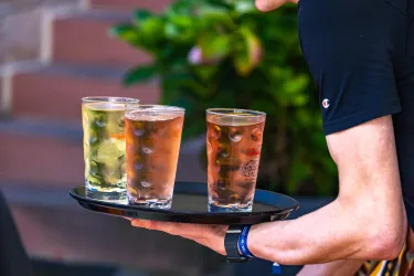 Ein Tablett mit drei Getränken in Gläsern. Die Drinks sind in verschiedenen Farben und es ist ein sonniger Tag.