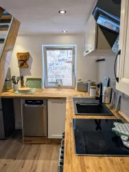 Eine moderne Küche mit Holzarbeitsflächen und einem Fenster, das viel natürliches Licht hereinlässt. Die Ausstattung umfasst einen Geschirrspüler und einen Herd.