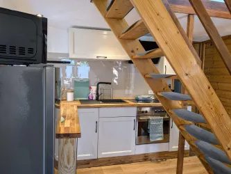 Eine moderne Küche mit hellen Möbeln und einer Holztreppe. Der Raum ist gut beleuchtet und bietet eine gemütliche Atmosphäre.