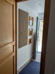 Ein heller Eingangsbereich mit einer Holzfütterung an der Wand. Die Tür führt nach draußen und es gibt einen Teppich am Boden.