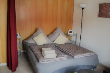 Ein gemütliches Schlafzimmer mit einem Doppelbett und zwei Kissen. Neben dem Bett stehen ein Nachttisch und eine Lampe.