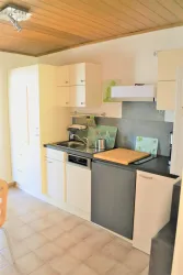 Eine moderne Küche mit hellen Schränken und einer Arbeitsfläche aus Holz. Sie ist gut ausgestattet und bietet viel Stauraum.