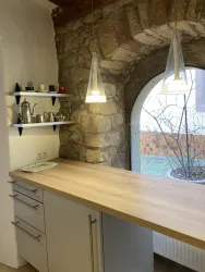 Eine moderne Küche mit einem Holzarbeitsplatz und einer Steinwand. Über dem Tisch hängen zwei stilvolle Pendelleuchten.
