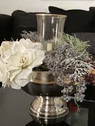 Eine elegante Blumenvase mit weißen Blumen und dekorativen Beeren. Im Inneren der Vase befindet sich ein Kerzenhalter.