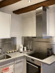 Moderne Küche mit Edelstahlgeräten:  Geschirrspülmaschine, Herd mit Backofen, Mikrowelle, Filterkaffeemaschine und Coffeepress Maschine, Milchaufschäumer und Wasserkocher.