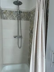 Eine moderne Dusche mit einer eleganten Duschbrause und Duschvorhang. Die Wände sind mit einem floralen Muster dekoriert.