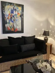 Über dem schwarzen Sofa hängt ein abstraktes Gemälde von Prof. Dr. Dellwing.