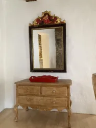 Ein schöner Holztisch mit einer roten Schale und einem großen Spiegel darüber. Der Raum hat helle Wände und einen warmen Holzfußboden.