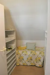 Ein kleines Zimmer mit einem Bett und Regalen. Die Wände sind hell, und es sind frische Handtücher aufbewahrt.