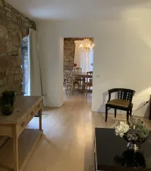 Ein gemütliches Wohnzimmer im Landhausstiel. Im Hintergrund ist ein Essbereich mit einem Kronleuchter zu sehen.