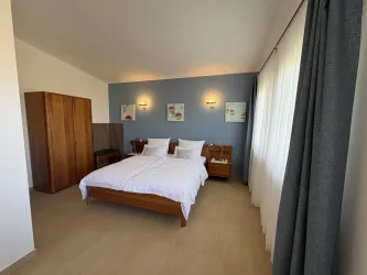 Ein helles Schlafzimmer mit einem großen Doppelbett und Holzmöbeln. Die Räume sind freundlich gestaltet und gut beleuchtet.