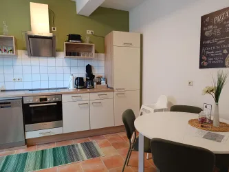 Eine moderne Küche mit klaren Linien und funktionalem Design. Ein runder Tisch mit Stühlen lädt zum Verweilen ein.