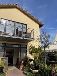 Ein schönes Gebäude mit einem Balkon und einer Terrasse. Umgeben von Pflanzen und einer einladenden Atmosphäre.