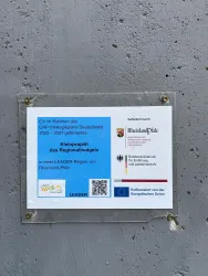 Ein Plakat, das ein gefördertes Projekt im Rahmen des Regionalbudgets zeigt. Es enthält Informationen über die LEADER-Region Rheinland-Pfalz und Logos verschiedener Institutionen.