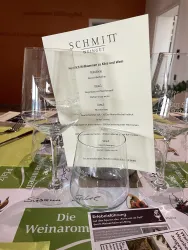Ein elegant gedeckter Tisch mit Gläsern und einer Menükarten. Die Dekoration lädt zu einer Weinverkostung ein.