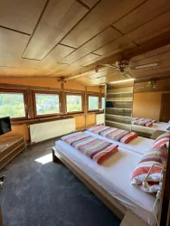 Ein gemütliches Schlafzimmer mit zwei Einzelbetten und bunten Kissen. Große Fenster bieten einen schönen Blick und viel Tageslicht.