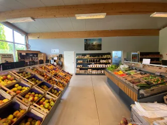 Ein kleiner, einladender Verkaufsraum mit Regalen voller frischer Obst- und Gemüsesorten. Auf der linken Seite befinden sich Obstkisten, rechts eine Auswahl an Gemüse. Hofladen Obsthof Puder in Laumersheim.