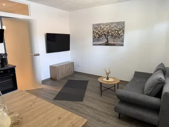 Ein modernes Wohnzimmer mit einem grauen Sofa und einem Kaffeetisch. An der Wand hängt ein Bild eines blühenden Baumes.