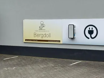 Ein auffälliges Schild mit dem Namen "Bergdoll". Es zeigt auch ein Symbol für eine Ladestation.