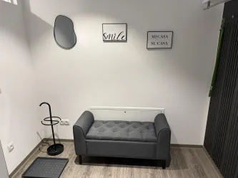 Ein eleganter Raum mit einer grauen Couch und einem runden Spiegel. An der Wand hängen inspirierende Bilder mit Schriftzügen.