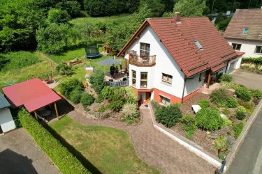 Ein schönes Einfamilienhaus mit einem gepflegten Garten. Der Außenbereich verfügt über Sitzgelegenheiten und eine Spielmöglichkeit.