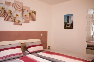 Ein gemütliches Schlafzimmer mit zwei Betten und einer dekorativen Wandgestaltung. An der Wand hängen Bilder von Orchideen und einem turmähnlichen Bauwerk.
