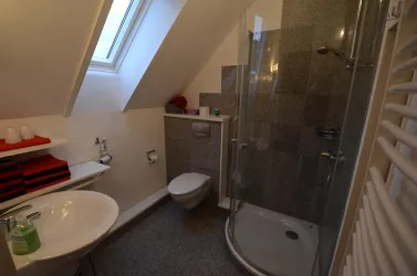 Ein modernes Badezimmer mit Dusche und Waschbecken. Hell und gut ausgestattet mit natürlichen Lichtquellen.