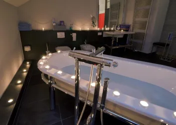 Ein modernes Badezimmer mit einer eleganten Badewanne und sanfter Beleuchtung. Kerzen und stilvolle Dekoration schaffen eine entspannte Atmosphäre.