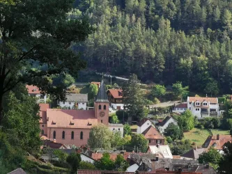 Das malerische Dorf Lindenberg (Pfalz), umgeben von Wäldern und Hügeln. Im Vordergrund steht die katholische Kirche mit ihrem charakteristischen Turm.
