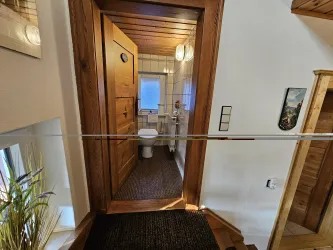 Ein einladender Flur mit einer Holztür, die zu einem Badezimmer führt. Die Wände sind hell und die Einrichtung ist gemütlich.