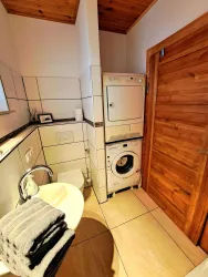 Ein modernes Badezimmer mit einer Waschmaschine und einem Trockner. Es gibt Handtücher auf dem Waschbecken und eine Holzschiebetür.